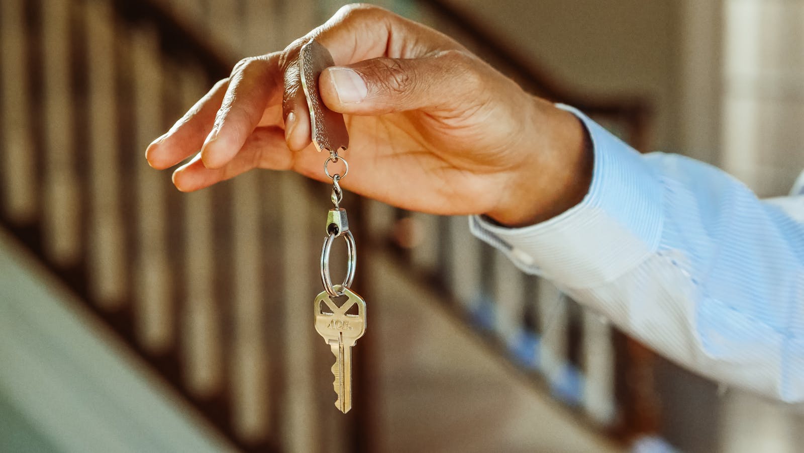 A close-up shot of a hand holding a house key, indicating new ownership or renters